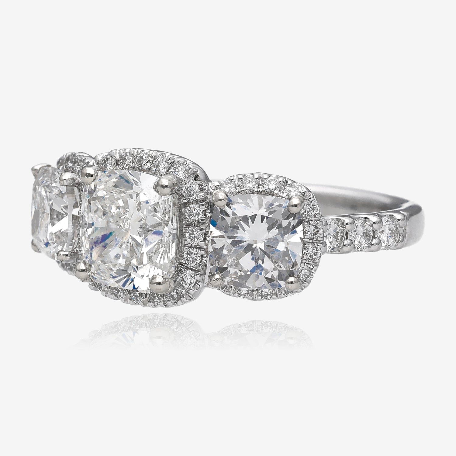 Side view of white gold ring with three large cushion shaped diamonds surrounded in smaller diamond accents