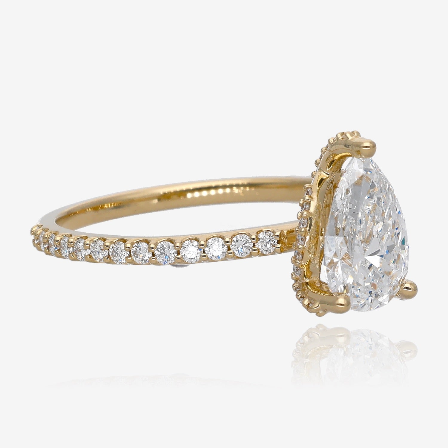 Sideview of yellow gold ring with large pear-shaped diamond. Diamond setting is set with several small accent gems. Ring shank is set with European set small diamonds all the way down.