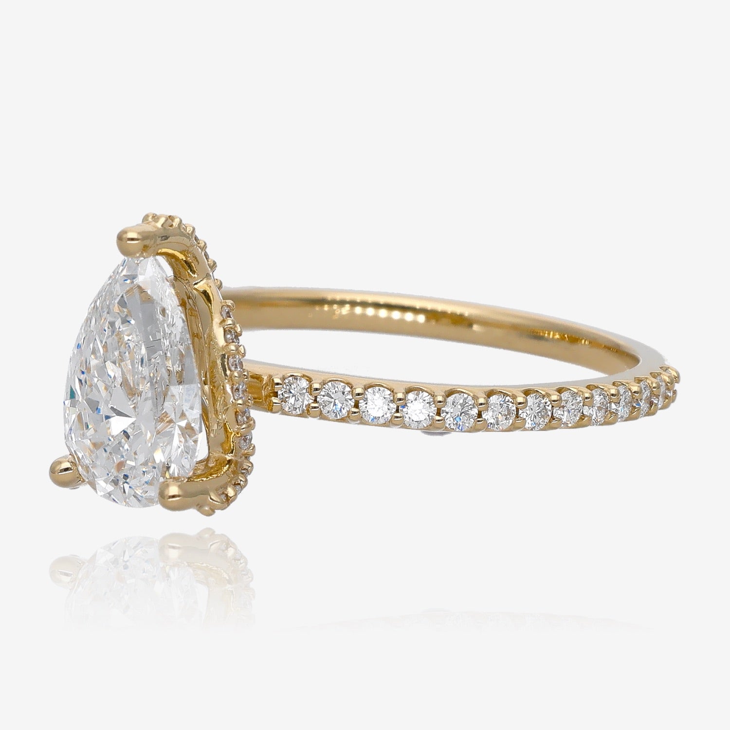 Sideview of yellow gold ring with large pear-shaped diamond. Diamond setting is set with several small accent gems. Band has French set small diamonds all the way down.