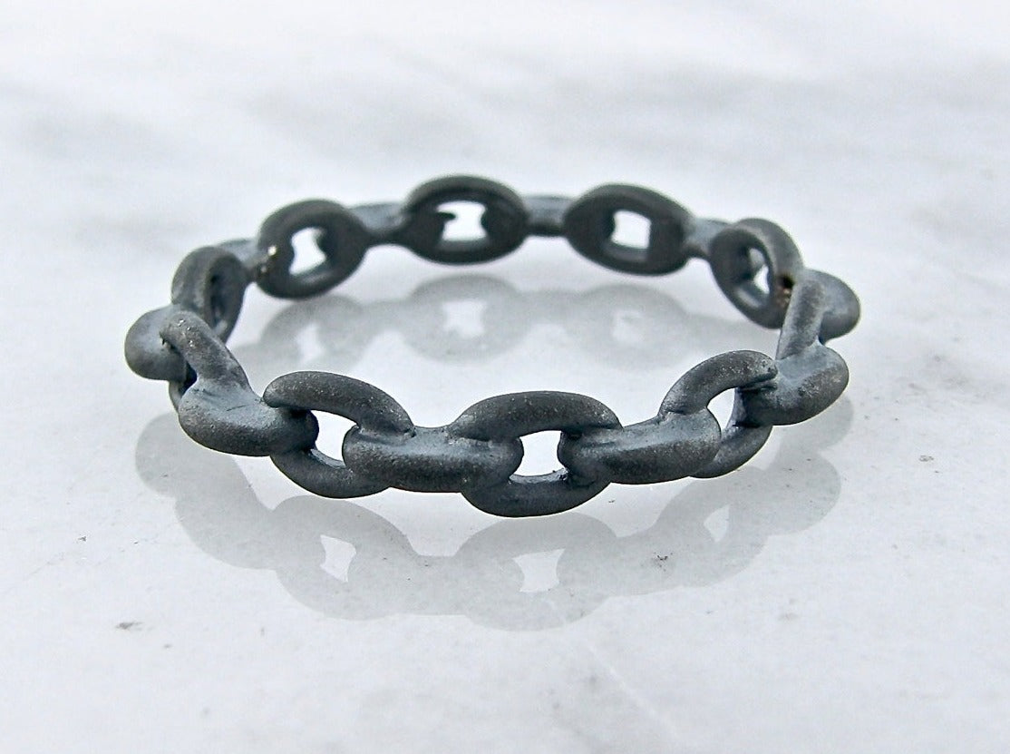 matte black silver ring comprised of oval chain links fused into a ring shape