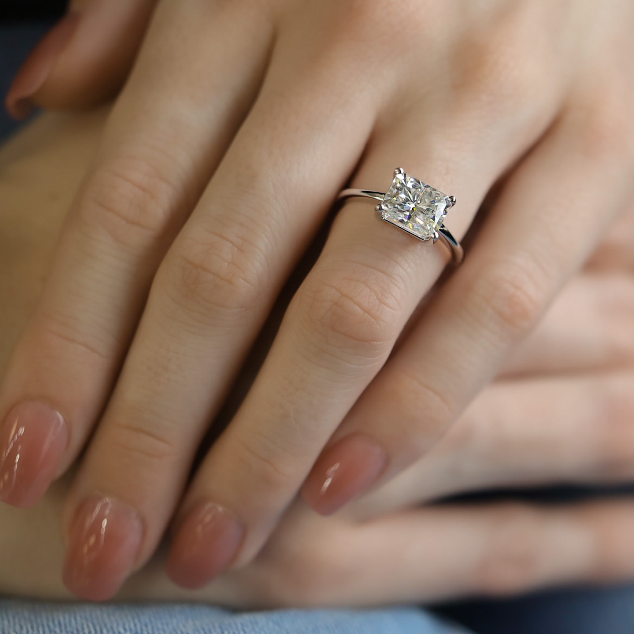 Horizontal rectangle radiant white gemstone engagement ring two carats. Set in white gold and four prongs, shown on a woman’s hand