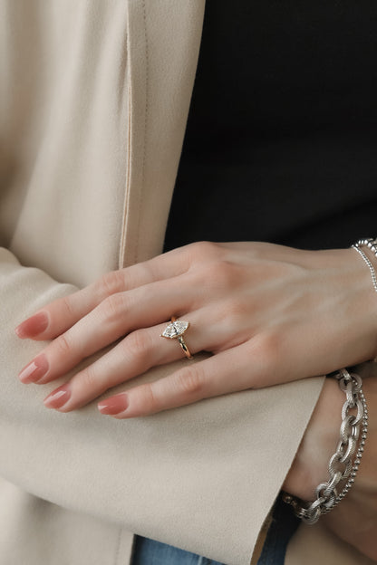 Image shows Woman’s hand wearing a yellow gold marquise diamond solitaire ring with a slender band and size prongs