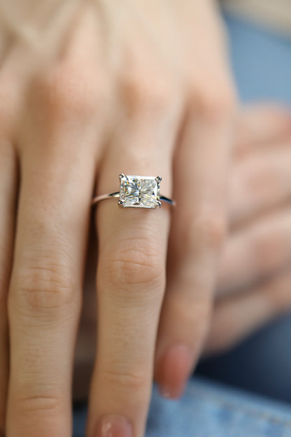 Woman’s hand wears a large rectangular radiant cut white Moissanite set east west 