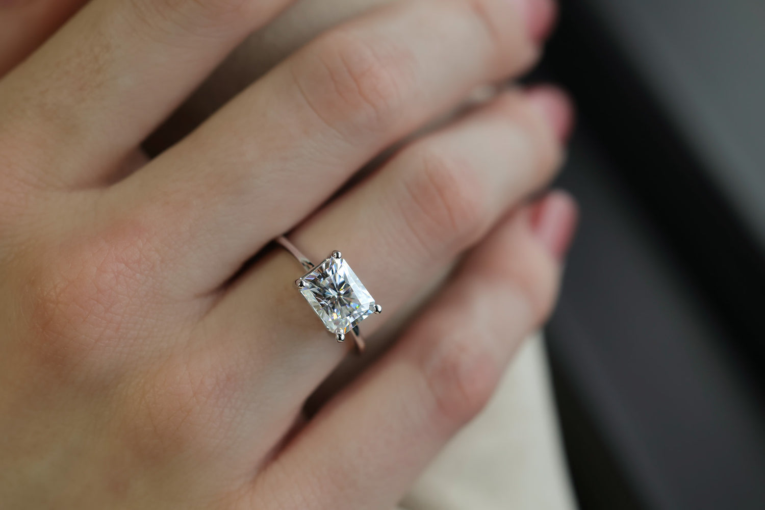 East west Horizontal rectangle radiant white gemstone engagement ring two carats. Set in white gold and four prongs, shown on a woman’s hand