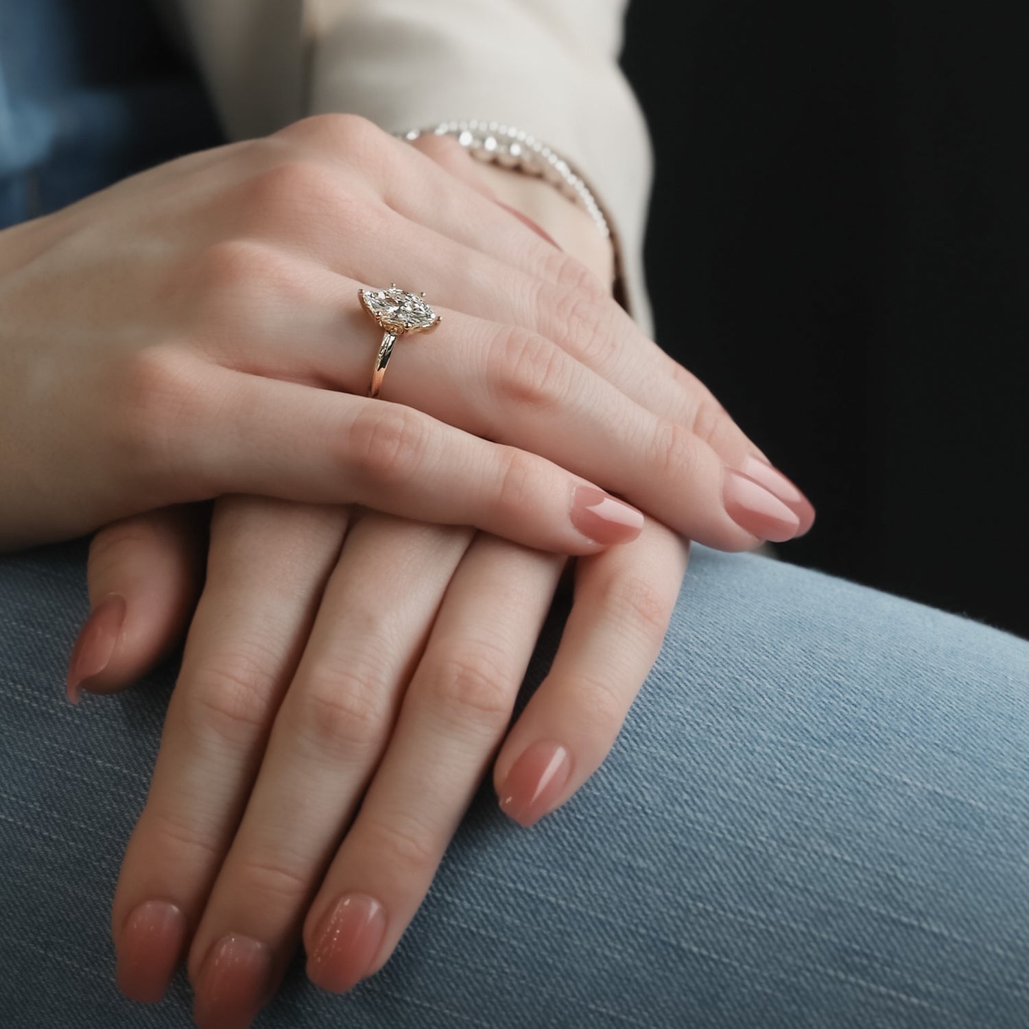 Woman’s hand wearing a yellow gold marquise diamond solitaire ring with a slender band and size prongs