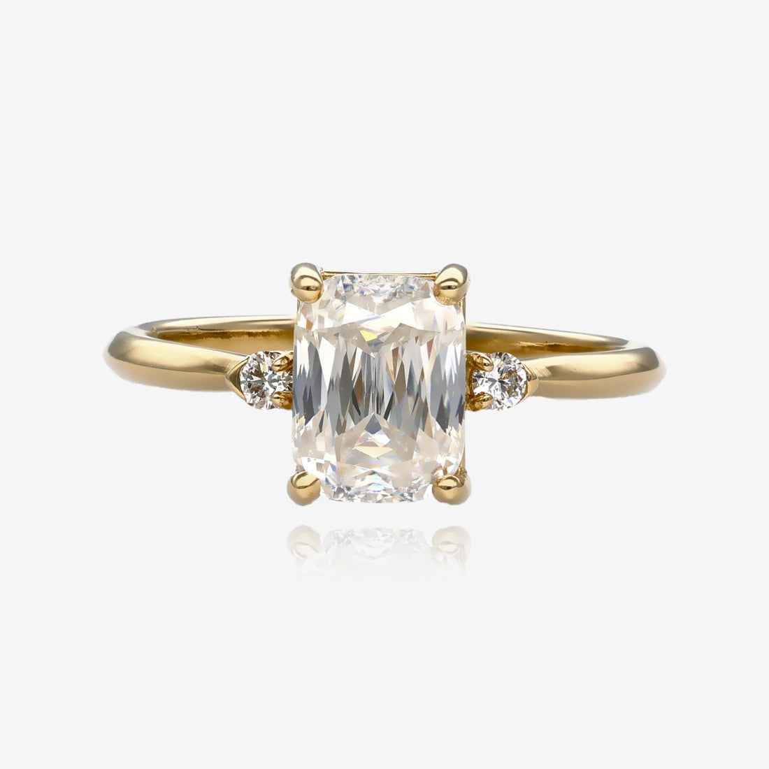 Ring shows a medium size, scissor cut, cushion shape moissanite in a slender yellow gold band with a small diamond on each side 