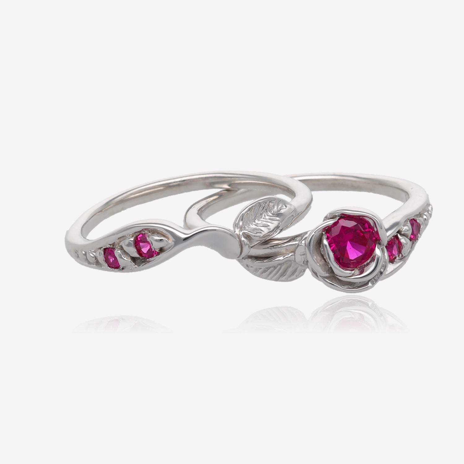 two rings loosely stacked on each other, with the bottom ring being the main engagement ring with a 4mmround deep pink gemstone