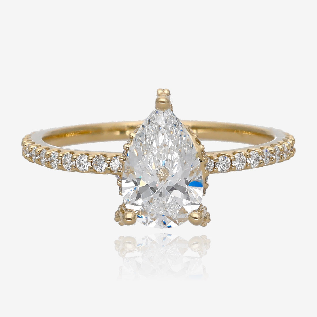 Pear-shaped diamond in 14 K yellow gold setting set with three prongs covered in tiny diamonds. Thin band on side features small diamonds, reaching around almost to the bottom of the ring.