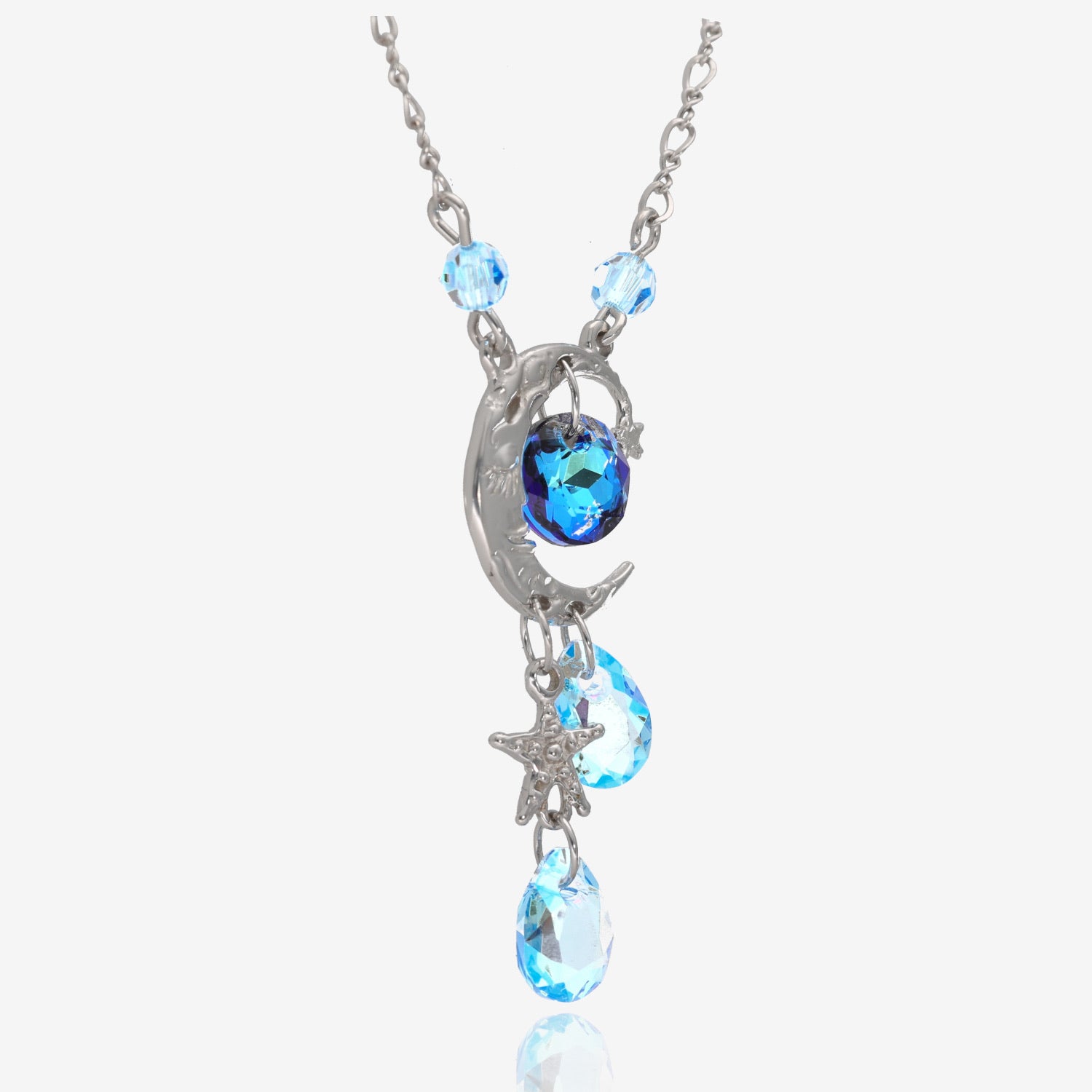 3/4 view of a silver pendant shaped like a crescent moon. Attached are 4 light blue gem beads, a star charm on the bottom, and a dark blue gem bead in the center of the crescent. Chain attached at the sides on top of the pendant to 2 of the 4 light blue gem beads.