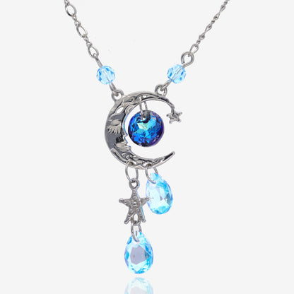 Front view of a silver pendant shaped like a crescent moon. Attached are 4 light blue gem beads, a star charm on the bottom, and a dark blue gem bead in the center of the crescent. Chain attached at the sides on top of the pendant to 2 of the 4 light blue gem beads.