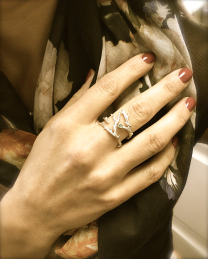 A ring comprised of slender interconnected twigs. The branches span approximately an inch on top, and in the center is a small green gem bezel set