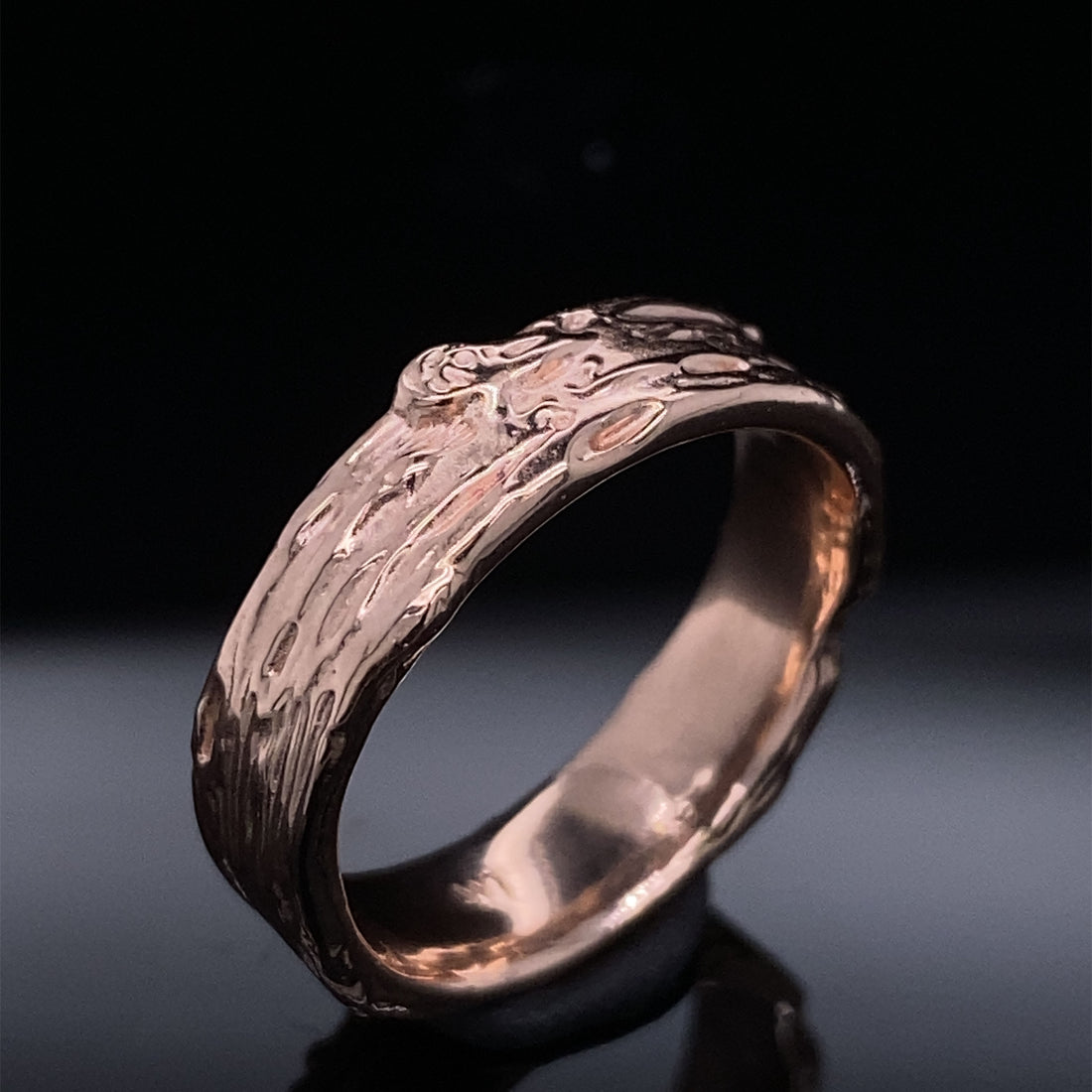 Black back ground with a thick rose gold band 6mm wide, with raised and recessed lines resembling birch bark. Texture includes knots and divots and slight rough areas.