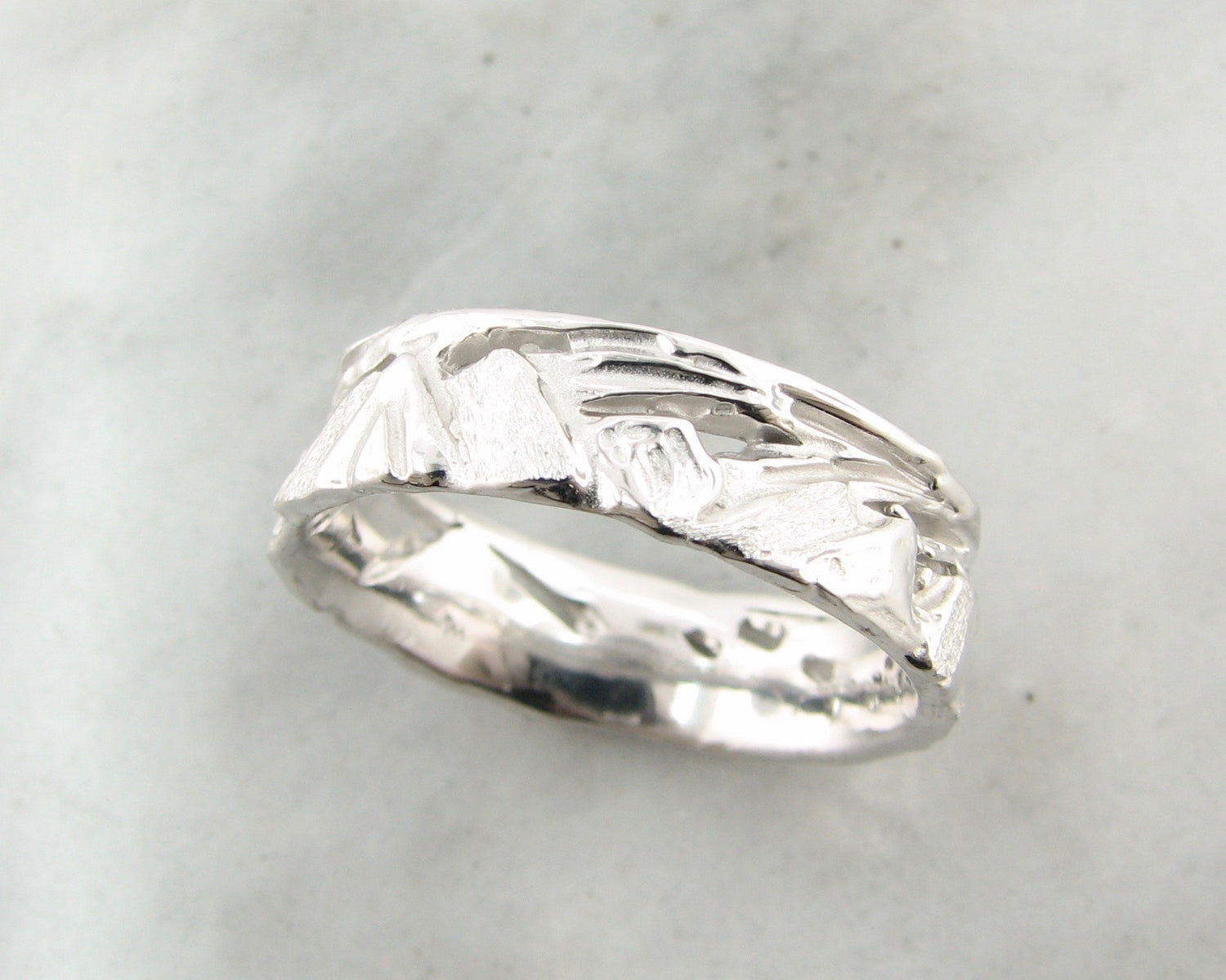 IMAGE SHOWS 6MM WIDE silver band with jagged mountain peaks sculpted all around. Ring is rustic with a rounded inside and rolled edges